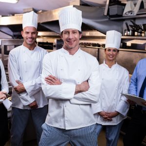 Portrait of happy restaurant team standing together in commercial kitchen